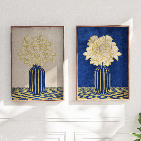 Two framed artworks of floral designs with blue and gold elements on a white wall.